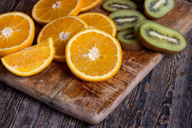 A top view closeup of half of a kiwi and half of orange put next to each other on an orange background