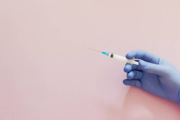 istock Hand in blue gloves holding syringe 1420149533