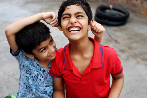 Two cheerful elementary age child of Indian ethnicity fighting together portrait close up at home.