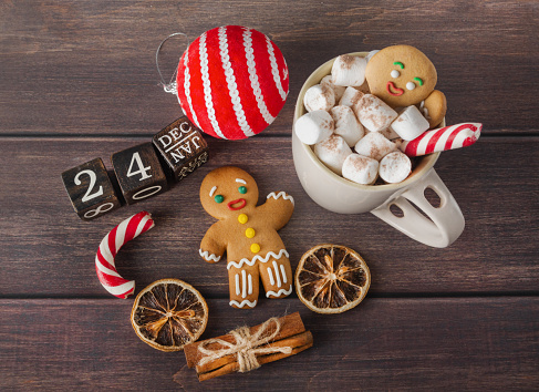 Christmas composition of a gingerbread man, coffee, sweets and a calendar on a brown background. New Year and Christmas concept. flat lay.