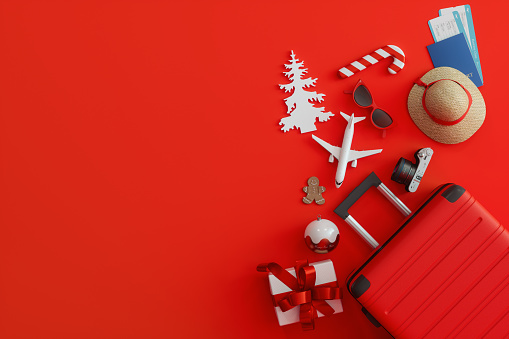 Christmas Travel Concept With Suitcase, Gift Box, Airplane Tickets And Christmas Ornaments On Red Background