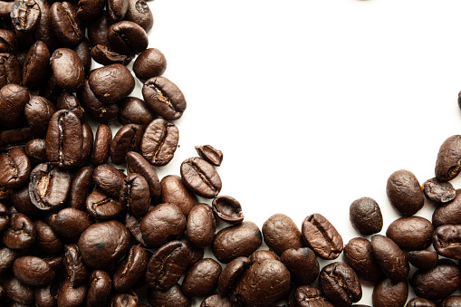 Brown roasted coffee beans falling , Represent breakfast, energy, freshness or great aroma,white background and bright wallpaper concept.close-up