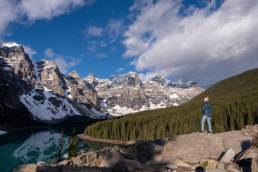 Hiker in Banff National Park. A female hiker stands and admires the beautiful Moraine Lake and surrounding mountains.
