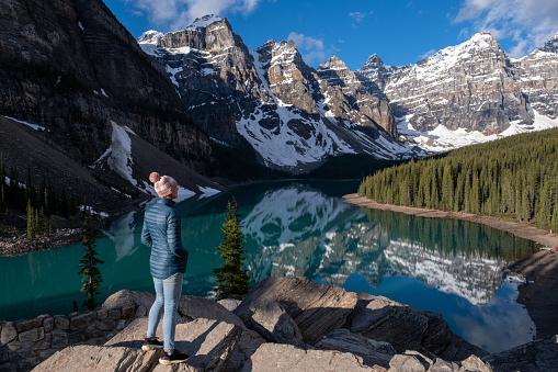 Hiker in Banff National Park. A female hiker stands and admires the beautiful Moraine Lake and surrounding mountains.