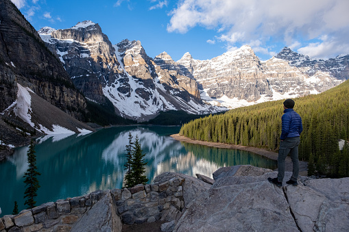 Hiker in Banff National Park. A male hiker admires the beautiful lake and surrounding mountains. Top tourist attractions when visiting the Banff National Park