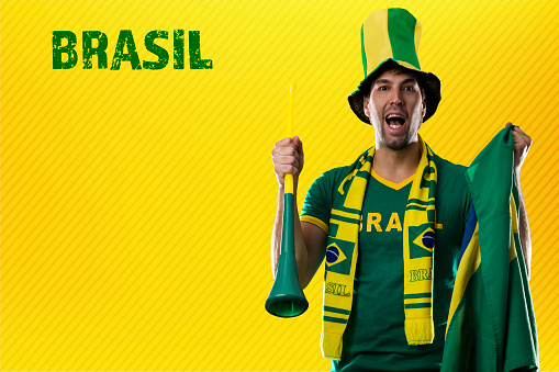 brazilian fan, man celebrating on a yellow background.