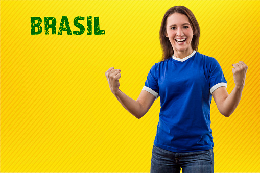 brazilian fan, woman celebrating on a yellow background.