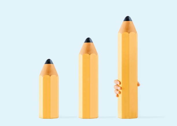 istock Minimal abstract concept of difficult writing and drawing exercises with yellow pencils lined up lengthwise and a child's hand holding the largest pencil. Back to school idea. Pastel blue background. 1420160199