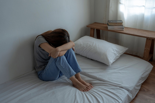 Asian woman sitting in bedroom alone, She suffers from depression, She was always stressed and anxious.