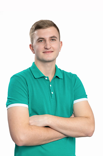 Portrait of a massage therapist on a white background. A young man stands with crossed arms.