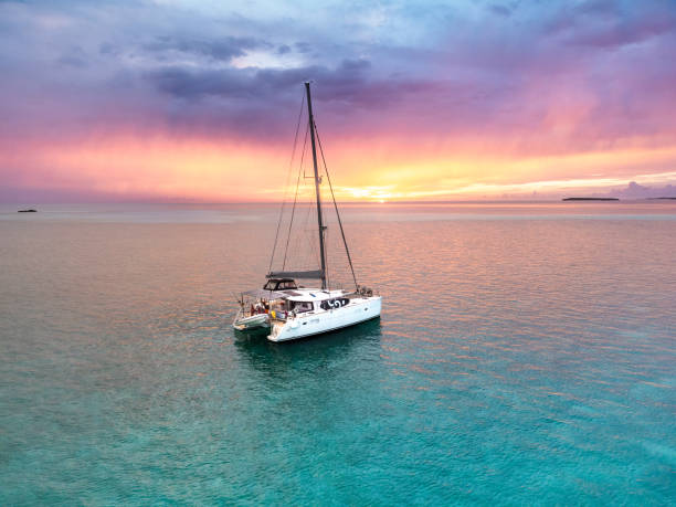 catamaran à voile ancré caraïbes bahamas turquoise eau coucher de soleil - anchored photos et images de collection