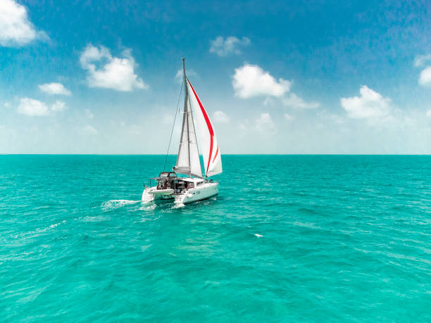 sailing catamaran caribbean bahamas turquoise water code 0 beautiful lagoon production catamaran is sailing through the clear waters of the bahamas sailboat mast stock pictures, royalty-free photos & images