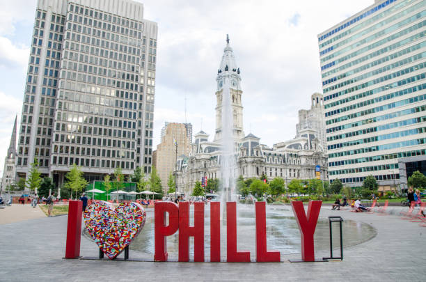 Philadelphia, United States - May 4, 2015: Love sculpture in the Love Park in Philadelphia, Pennsylvania, USA. People in the park. Skyline with skyscrapers on the background