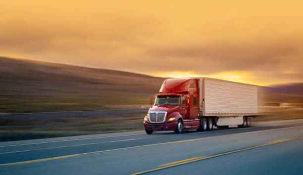 semi-remorque rouge et blanc transportant du merchandising au coucher du soleil - flou de mouvement - semi truck truck highway red photos et images de collection