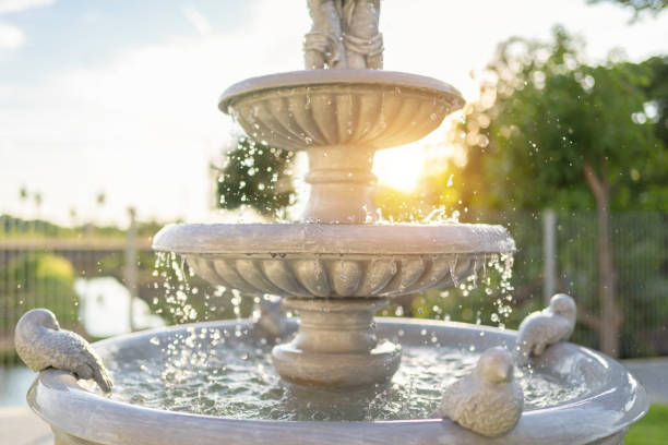 Streams of fountain water with sculpture statue with sun. Close-up of Garden waterfall in pond. Outdoor garden park. Relaxation. stock photo