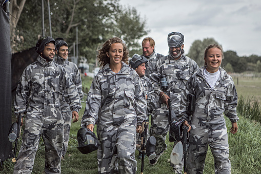 A mixed race, age and gender paintball team on their way to the field