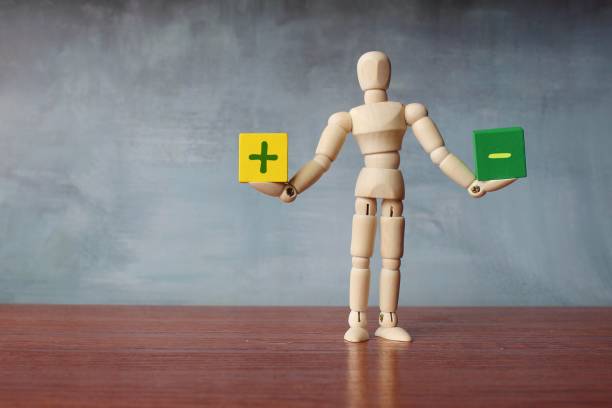 Pros and Cons balance concept. Pros and Cons balance concept. Wooden human figure balancing wooden cubes with plus and minus sign symbol. Copy space for text pros and cons stock pictures, royalty-free photos & images