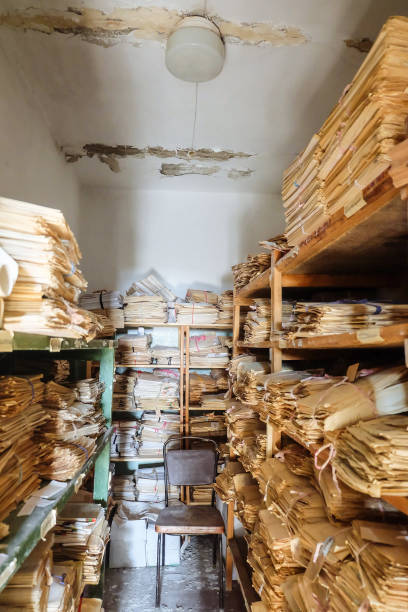 istock Room of an abandoned soviet administrative building with old archival paper documents on racks in piles 1420186255