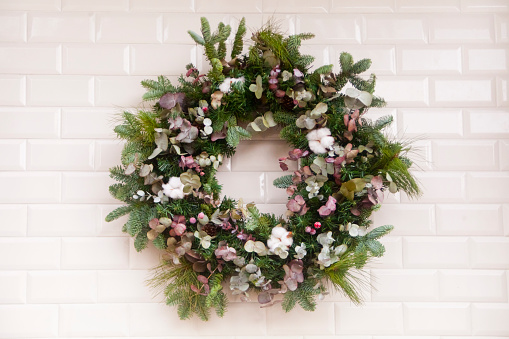 Decorative garland  hanging ,  front view, white vintage tiles background. Christmas decoration.