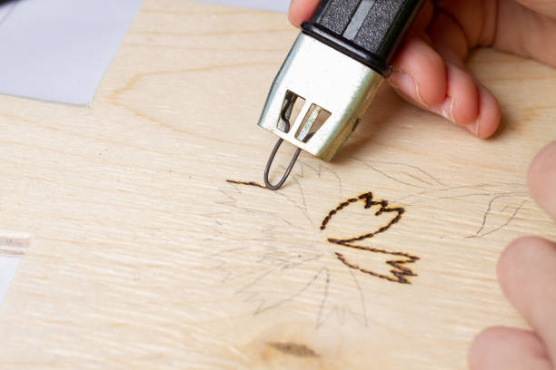 istock Burn out a drawing on a wooden board with an electric device with a scorcher 1420191442