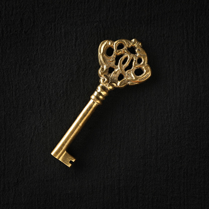 Single ornate skeleton key in shiny gold. Concept for unlocking opportunities, finding solutions, or achieving goals.