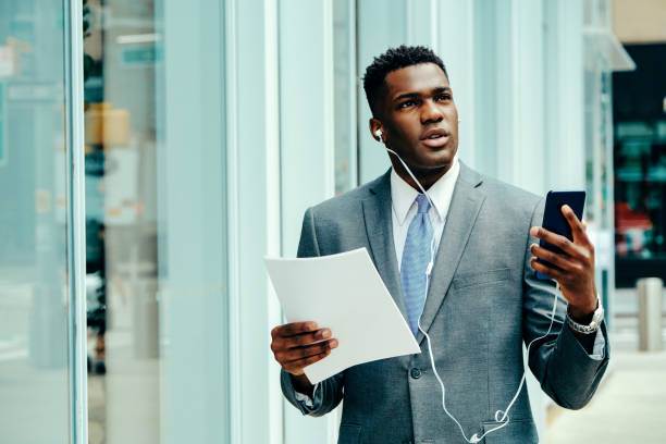 istock Young entrepreneur using smartphone outside wearing suit 1420205341