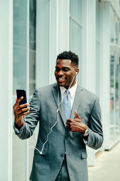 istock Positive young businessman using smartphone outside wearing suit 1420205346