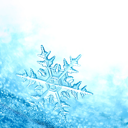 Sparkling blue background with clear shiny snowflake.
