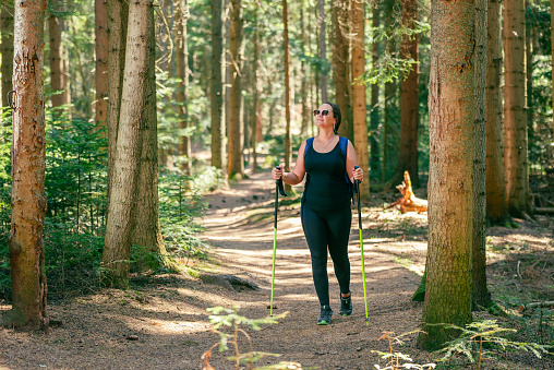 Woman walks through the forest on a well-trodden path. The concept of a healthy life, enjoying and playing sports in nature
