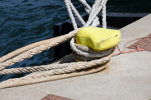 Boat bollard, ropes and knots in mediterranean harbor.