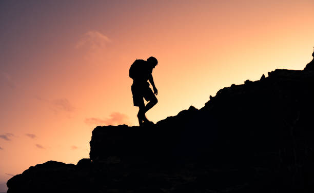 istock Silhouette of mountain climber climbing up rocky path. 1420207502