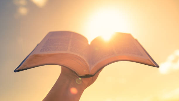 sosteniendo la biblia de la mano hasta la luz del sol. - bible book ideas inspiration fotografías e imágenes de stock