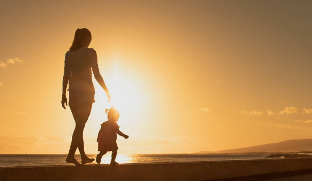 мама гуляет с дочкой малышом у моря - young family family with one child walking learning стоковые фото и изображения