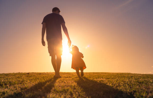 Father taking care of child, holding hands walking his little girl outdoors. stock photo