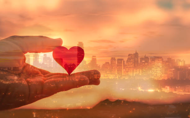 istock Hand holding heart against city background. 1420208726