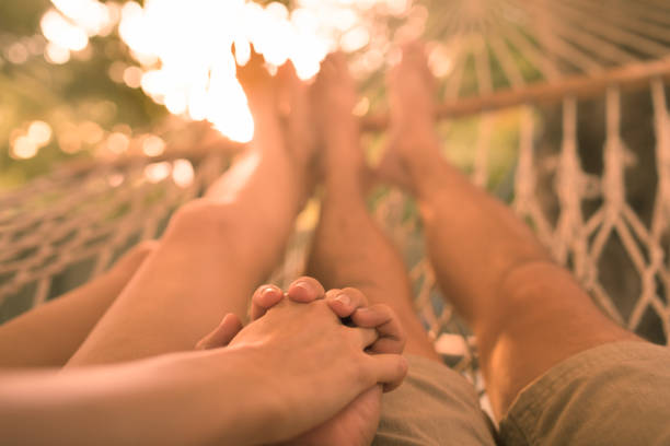 istock Couple holding hands relaxing in a hammock at sunset 1420208880