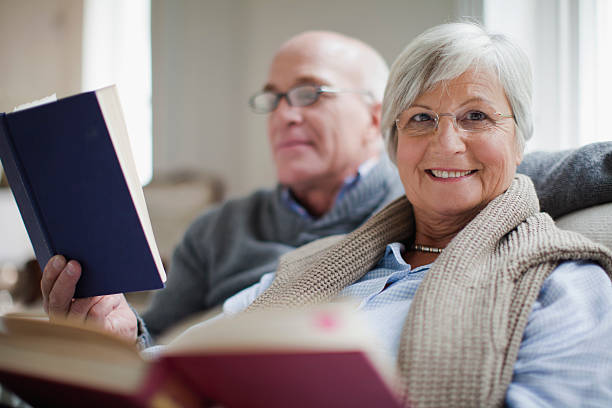 uśmiechająca się starsza para czytanie książki - biała kobieta czyta w okularach zdjęcia i obrazy z banku zdjęć