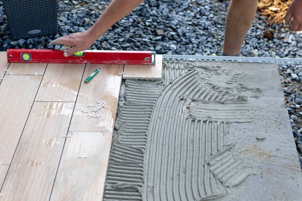 istock The hands of the professional tiler lying or installing modern, ceramic tile above cement on the garden terrace , tiling floor, building and pavement concept 1420213549