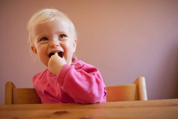 lächeln baby mädchen sitzt am tisch - @jackstar stock-fotos und bilder