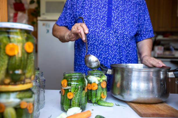 年配の女性による新鮮なバイオキュウリを瓶に自家製缶詰�にする工程、食品コンセプト - canning ストックフォトと画像