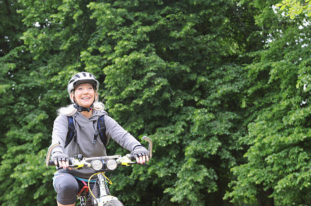 mulher mais idosa andar bicicleta na estrada rural - fey imagens e fotografias de stock