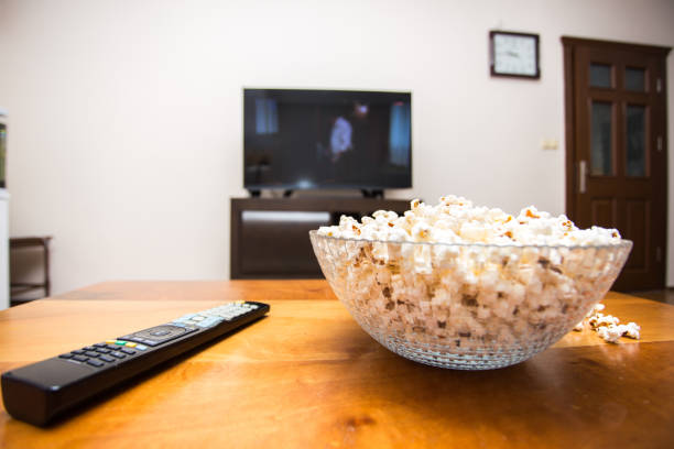 istock Tv remote control and popcorn on a wooden brown coffee table. 1420216511