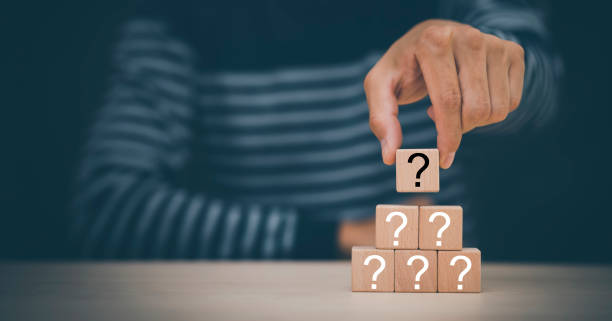 istock Hand hold Wooden cube block in question mark mean what on cement table background, column of wooden blocks with question sign mark. copy space,FAQ frequently asked questions, Answer, Information 1420221288