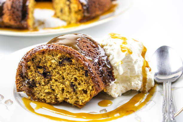 A slice of date pudding garnished with salted caramel sauce and fresh whipped cream.