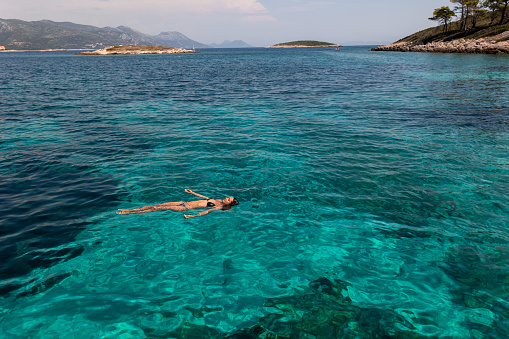 Young woman floating in fresh clean turquoise water .