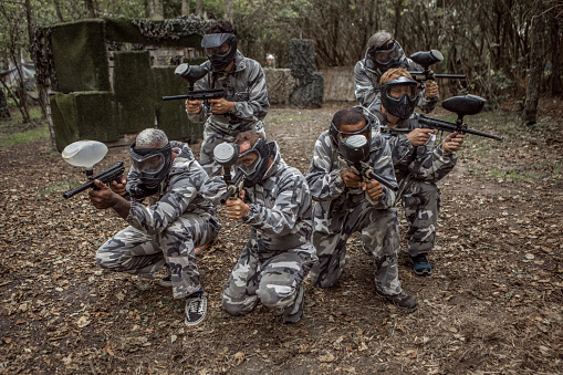 A mixed race middle aged male paintball team in action