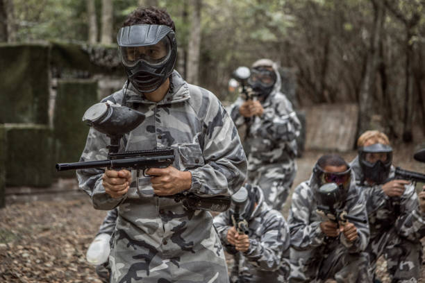 A mixed race middle aged male paintball team in action