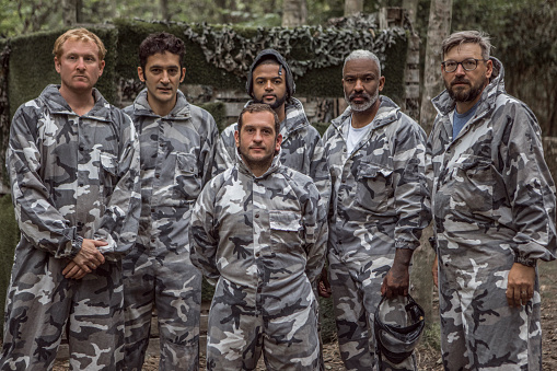 Portrait of a mixed race middle aged male paintball team on the field