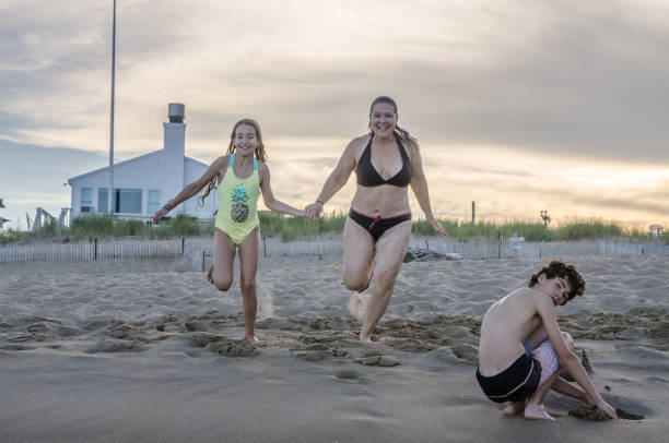 mother and daughter running into the atlantic ocean - plum imagens e fotografias de stock