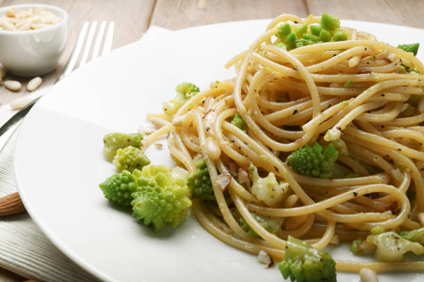 паста. спагетти с брокколи, миндалем, кедровыми орехами, орегано и оливковым маслом первого отжима крупным планом. - romanesco broccoli стоковые фото и изображения